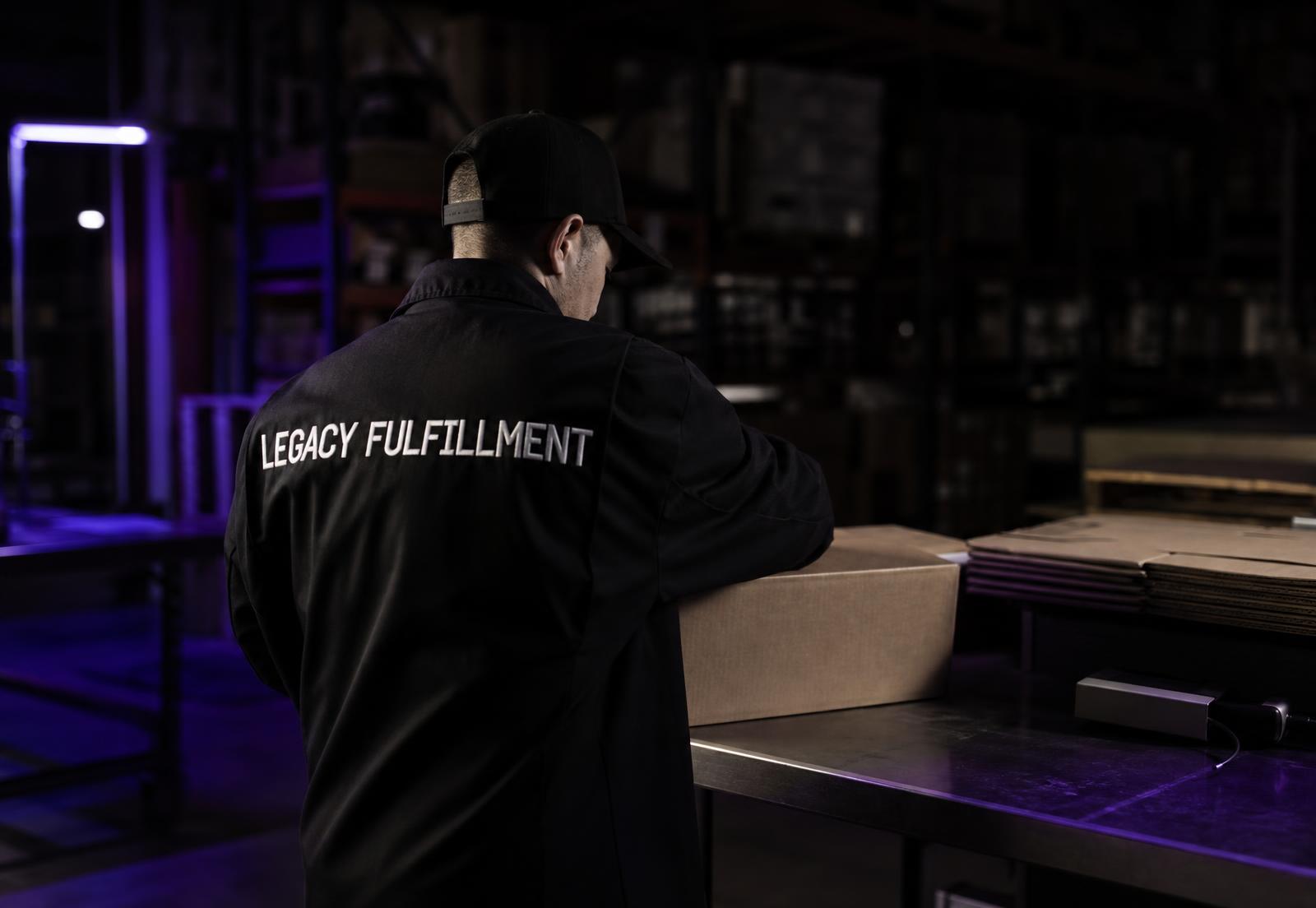 Legacy Fulfillment worker packing shipments, branded jacket